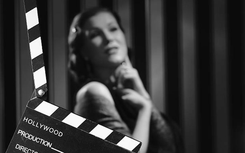 Hollywood black and white, a beautiful acting woman and a clapboard - minimal lighting and strong contrast