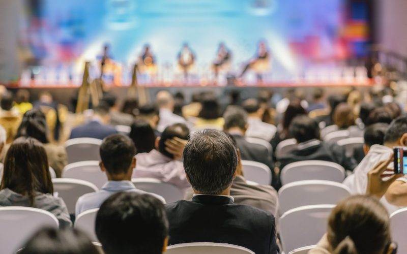 rear-view-of-audience-listening-speakers-on-the-stage-in-the-conference-hall-or-seminar-meeting-1-e1700247927731