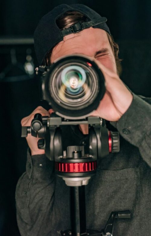 videographer-looking-through-camera-in-photo-studio